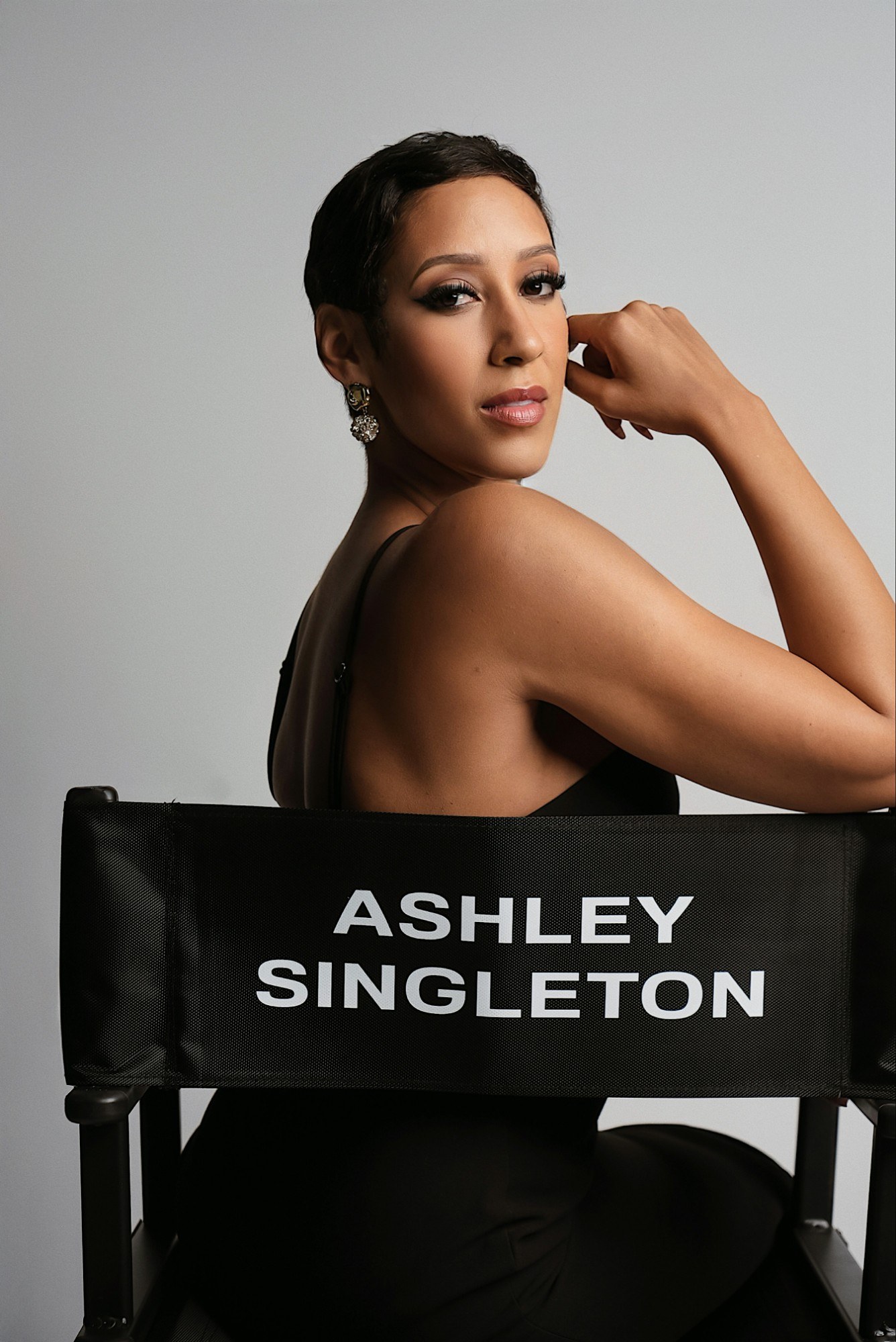 Ashley Nicole Singleton seated in a director's chair marked Ashley Singleton, looking over her shoulder